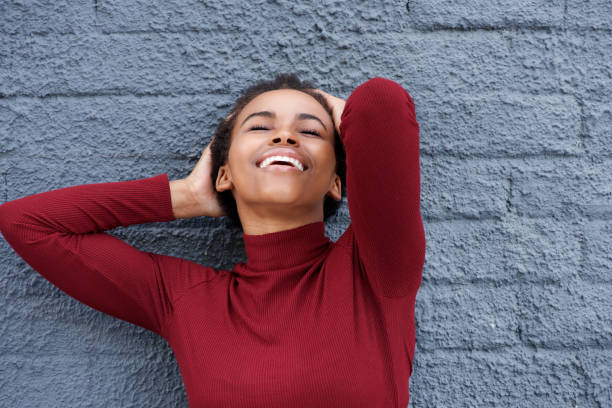 istock beautiful young african woman smiling with hand in hair 664734708