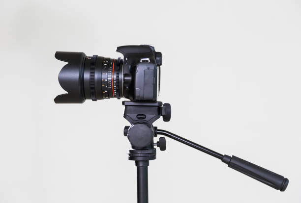 istock Digital SLR camera on a tripod with a removable manual lens on a gray background. Shooting in the interior. The equipment for filmmaking 664735168