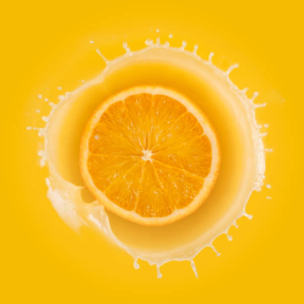 istock splashing orange juice with orange against yellow background 664737946