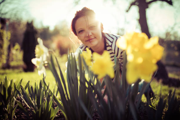 Young woman with daffodils in garden at sunny spring day