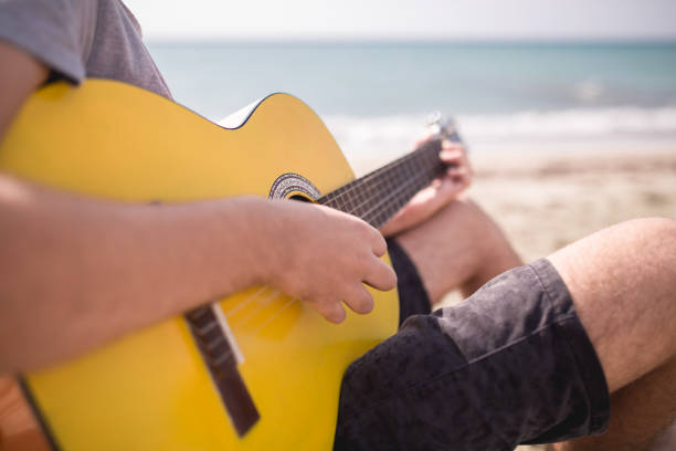 istock Cheerful handsome man playing guitar on the beach 664756706
