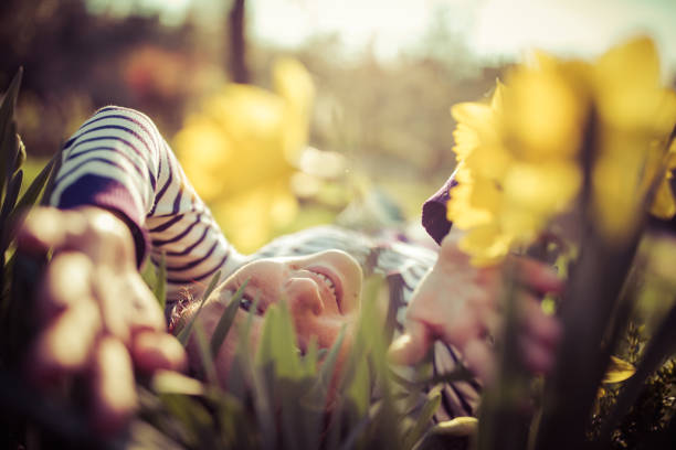 Young woman with daffodils in garden at sunny spring day