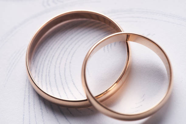 istock Two classical gold wedding rings on a white textured background 664758390