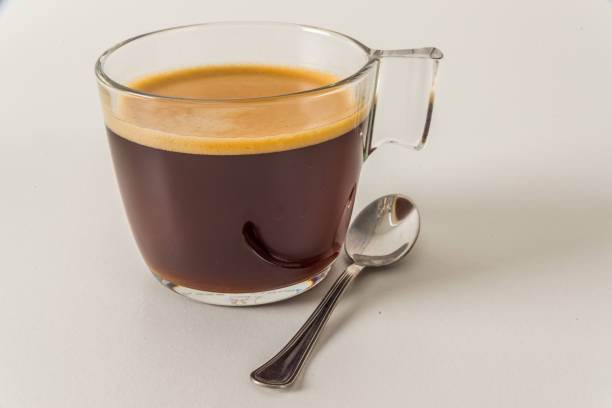 aroma black coffee in modern glass cup, white background, teaspoon, morning coffee