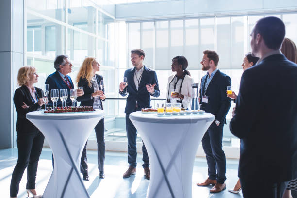 Celebrating their amazing success Business coworkers standing in a lobby. They are looking at each other and holding glasses of champagne and juice. black tie events stock pictures, royalty-free photos & images