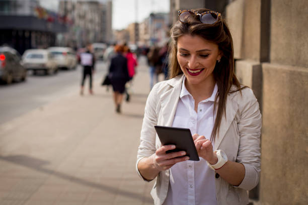 istock Beautiful brunette using digital tablet in the city 664778862