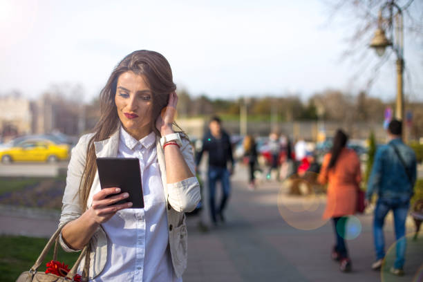 istock Beautiful brunette using digital tablet in the city 664779206