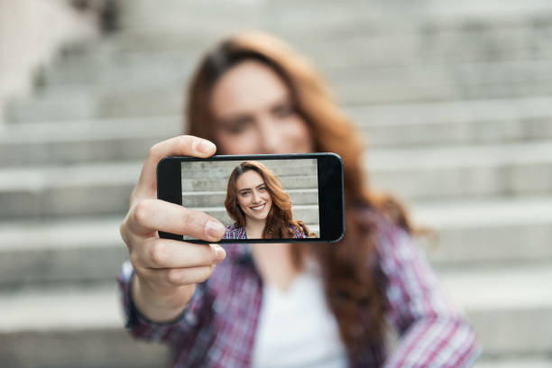 hermosa mujer hace retrato del uno mismo en vista del smartphone de pantalla - montar fotos fotografías e imágenes de stock