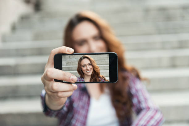 beautiful woman makes self portrait on smartphone view of screen - camera phone photo imagens e fotografias de stock