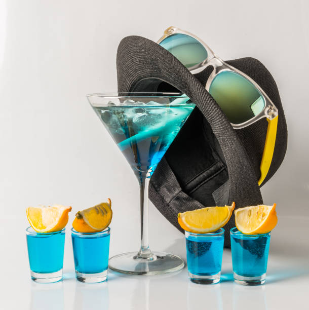 красочный напиток в бокале мартини, сине-зеленая комбинация, четыре напитка в песочных стеклах, черная шляпа, солнцезащитные очки - kamikaze cocktail drink lemon стоковые фото и изображения