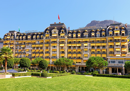 Montreux, Switzerland - August 27, 2016: Park and Luxury hotel and Swiss flag at Geneva Lake at Montreux, Swiss Riviera