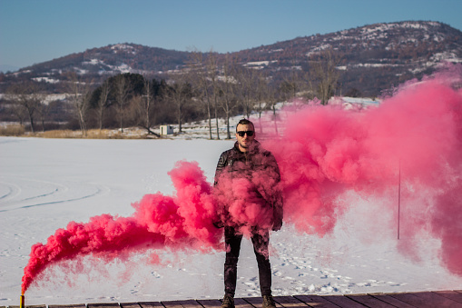 Man with red smoke cloud on frozen lake