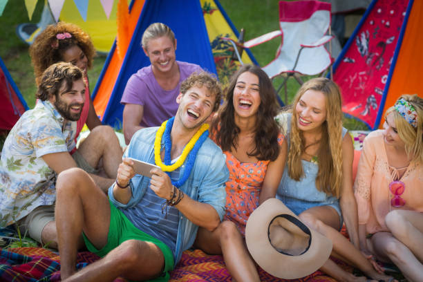istock Group of friends using mobile phone at campsite 664823596