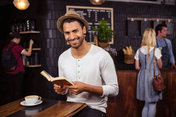 a man is reading a book and smiling - job search newspaper coffee shop cafe imagens e fotografias de stock