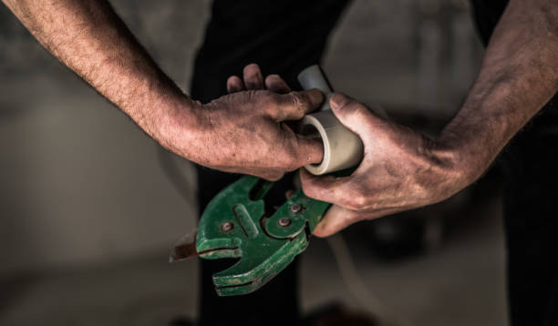 istock Manual worker's hands: the plumber cutting the plastic tubes with the special tools 664831628