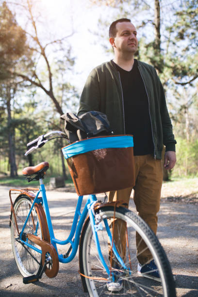 istock Young man with bicycle relaxing in park 664834716