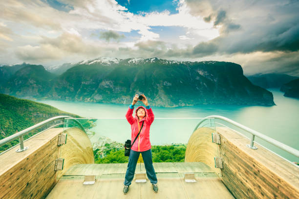 Tourist photographer with camera on Stegastein lookout, Norway Tourism and travel. Woman tourist nature photographer taking photo with camera, enjoying Aurland fjord landscape from Stegastein lookout, Norway Scandinavia. stegastein viewpoint stock pictures, royalty-free photos & images