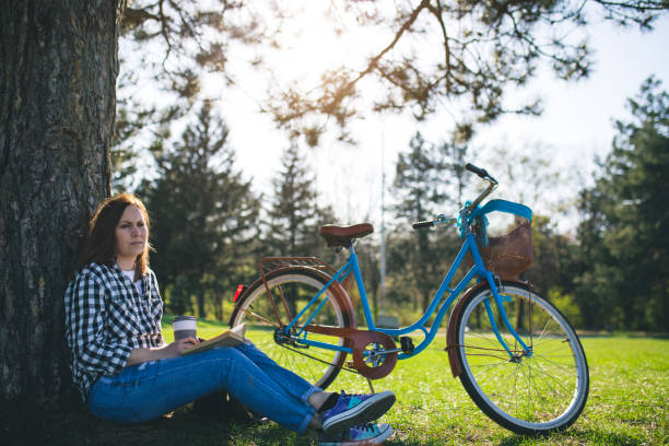 istock Happy young woman relaxing at park with bicycles 664841702