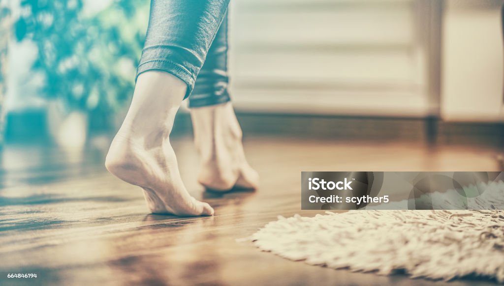 Warm floor - the concept of floor heating and wooden panels. Floor heating. Young woman walking in the house on the warm floor. Gently walked the wooden panels. Adult Stock Photo
