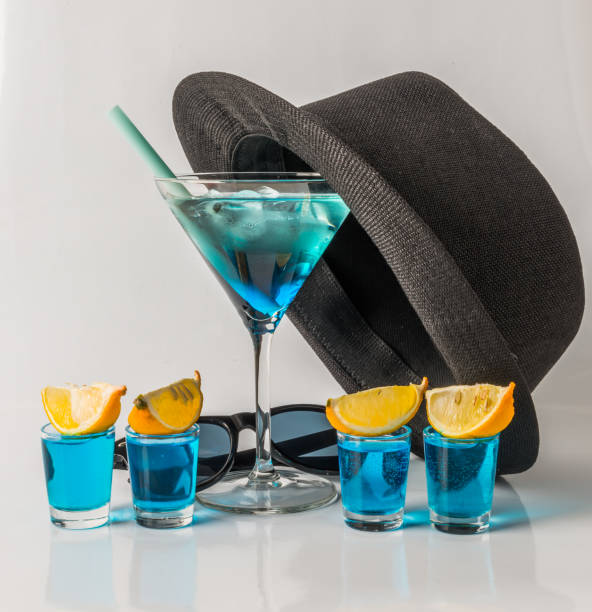красочный напиток в бокале мартини, сине-зеленая комбинация, четыре напитка в стакане, черная шляпа - kamikaze cocktail drink lemon стоковые фото и изображения