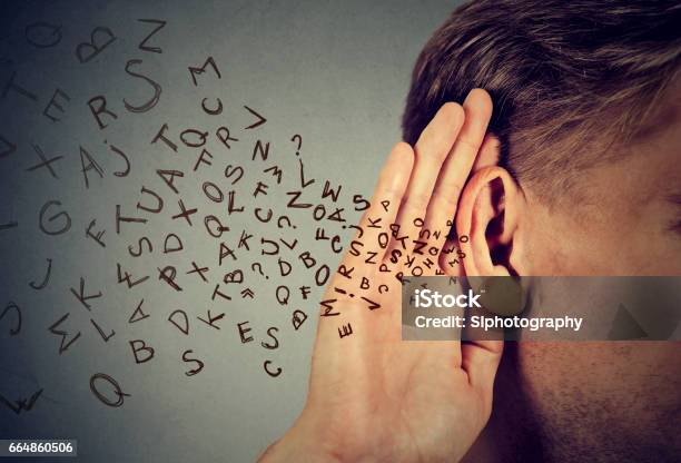 Man Holds His Hand Near Ear And Listens Carefully Alphabet Letters Flying Stock Photo - Download Image Now