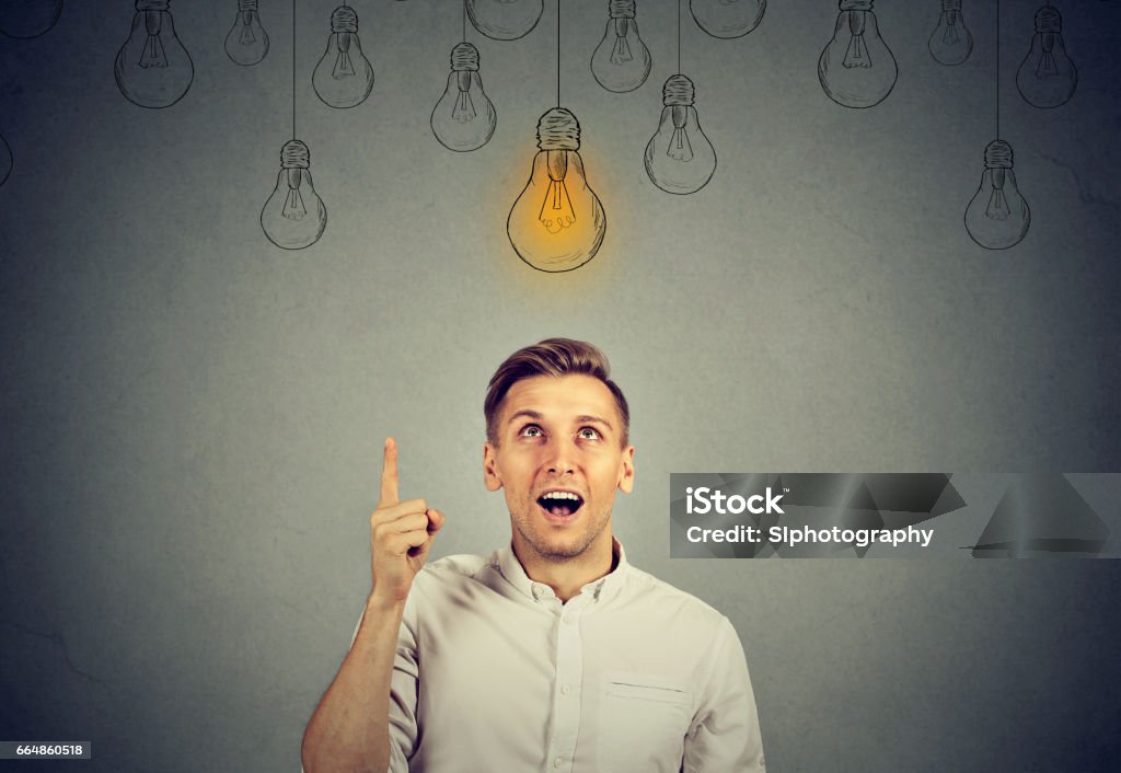 Glücklicher junger Mann, der auf Glühbirne zeigt, hat eine Lösung - Lizenzfrei Glühbirne Stock-Foto