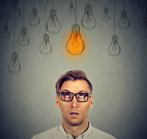 istock Excited man with many ideas light bulbs above head looking up 664860534
