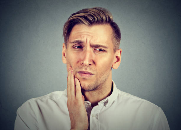 istock Portrait of young man with sensitive tooth ache 664861450
