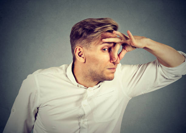 istock man pinches nose with fingers looks with disgust 664861476
