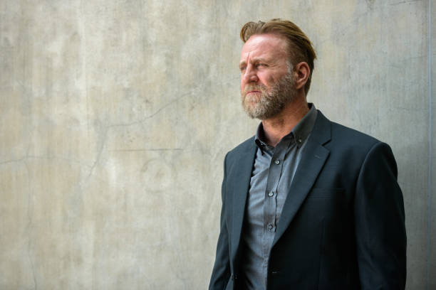 istock Mature bearded businessman thinking against urban concrete wall 664871856