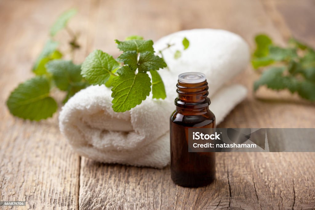 Mint essential oil Mint essential oil in a glass bottle, towel on an old wooden background Essential Oil Stock Photo