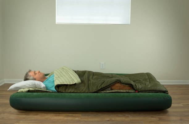 Man comfortably sleeping on blow up air mattress bed in sleeping bag stock photo