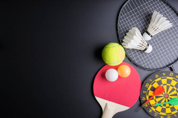 dardos, raqueta de tenis de mesa, ping pong, shuttlecocks, raqueta de bádminton y pelota de tenis sobre fondo negro. concepto deportivo, copia de imagen de espacio para tu texto. - rubber dart fotografías e imágenes de stock