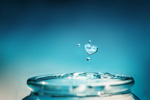 Close up of heart shape water drop falling down to the glass.