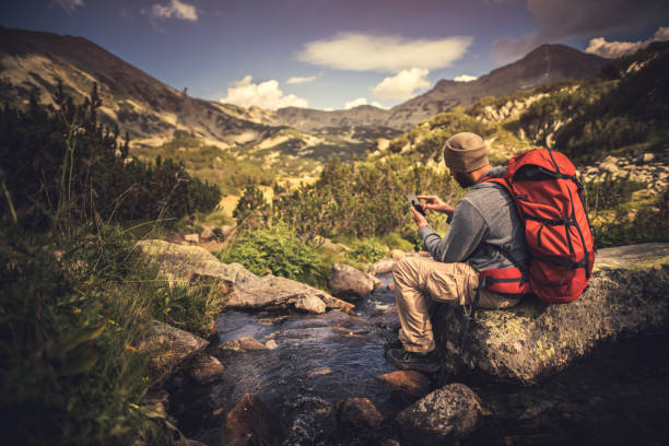 istock Traveler using a smartphone in the mountains 664896230