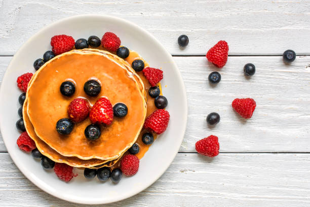 stack of pancakes with fresh berries and caramel sauce