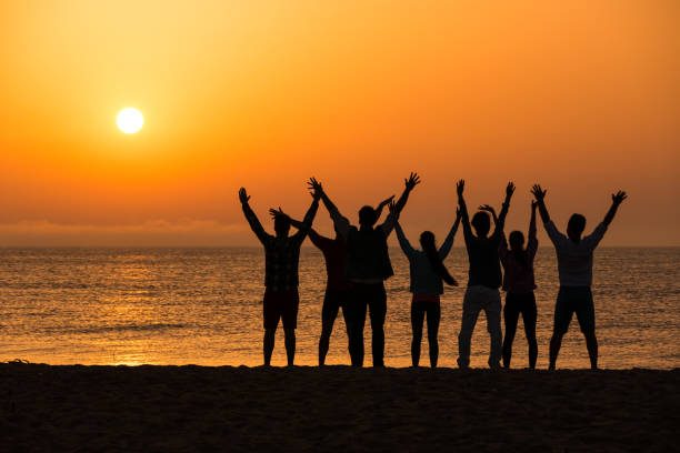 istock Group of people greeting the sun on beach 664903974
