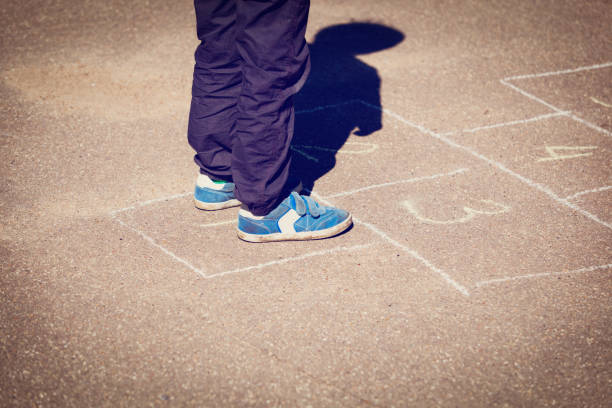 istock little boy playing hopscotch on playground 664908460