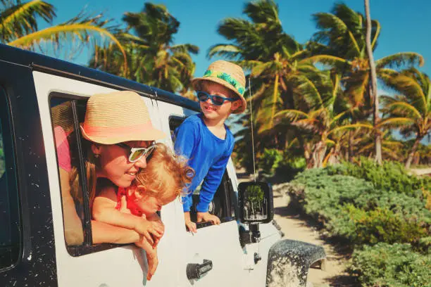 Photo of family driving off-road car on tropical beach