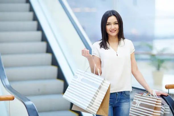 Shopper in casualwear standing by escalator