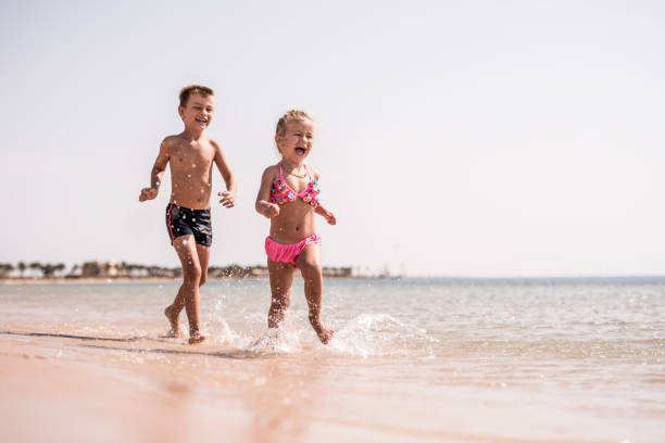 istock Joyful kids having fun while running on the beach. 664912916