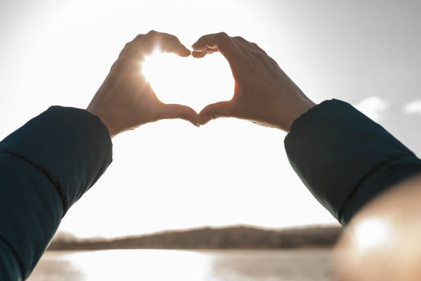 istock Girl holding hands in heart shape at beach 664917320