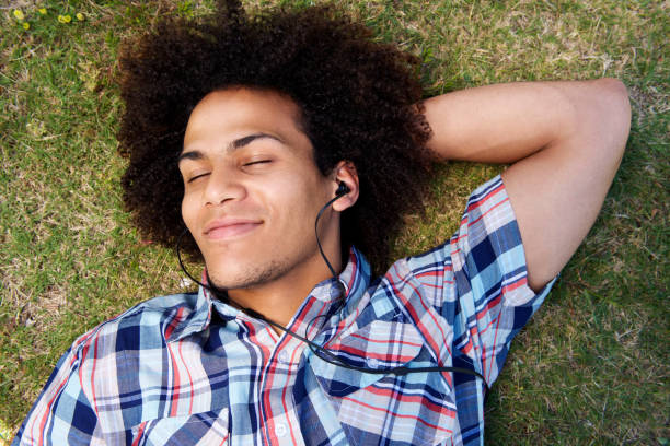 istock young man lying down on grass listening to music 664934162