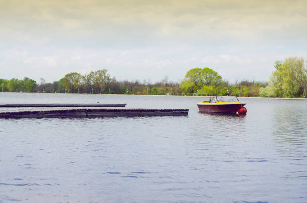 Wooden Pier In A Sunny Day With Parked Boat In Front Of It With Green Trees Behind