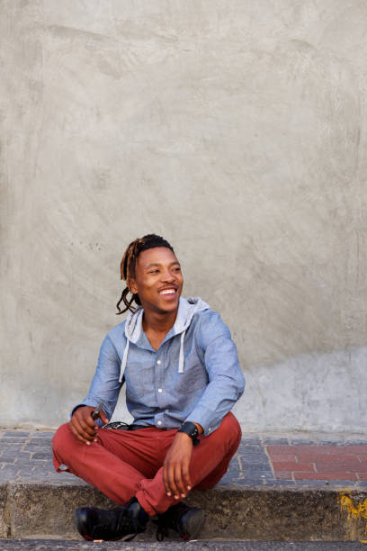istock happy african man sitting outside on sidewalk 664940248