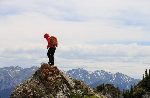 successful woman backpacker hiking on mountain peak cliff