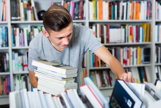 istock Positive teenager boy selecting for new book 664951058