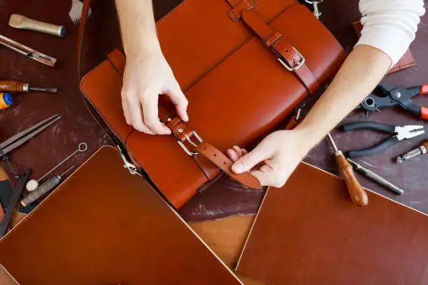 Tanner fastening one of buckles of new leather briefcase