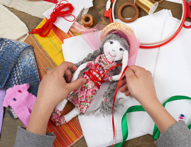 istock child hand making dress for handmade doll, learn to sewing 664963230