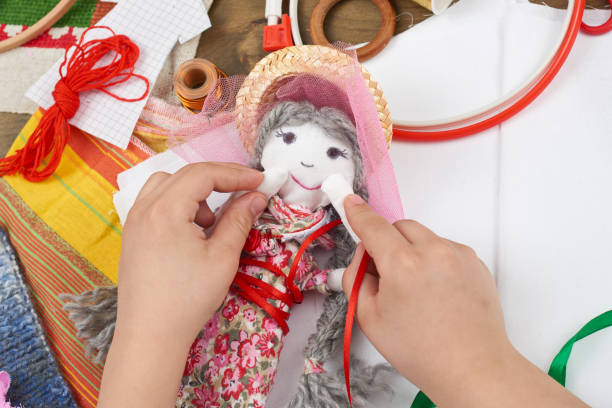 istock child hand making dress for handmade doll, learn to sewing 664963300